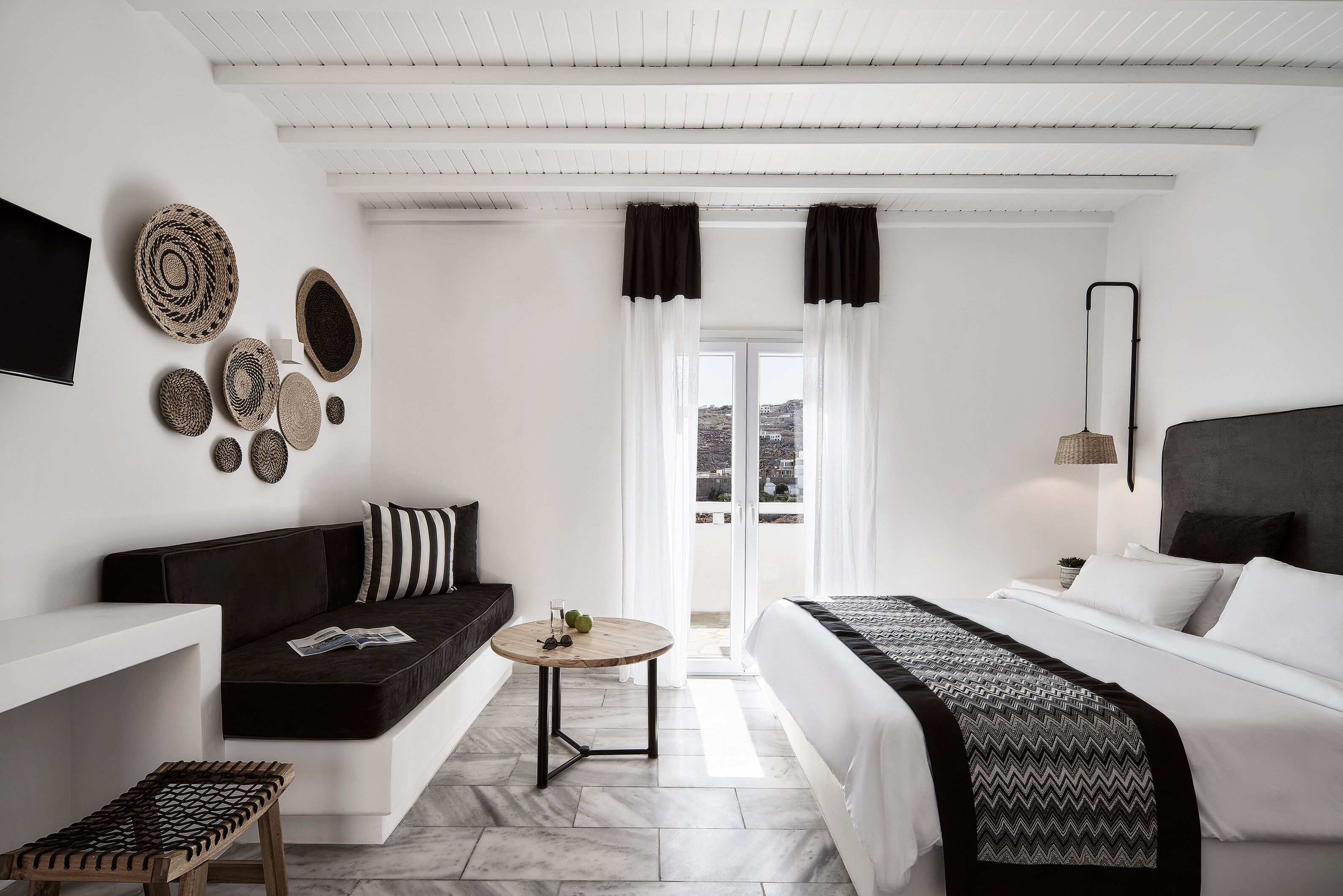 Una habitación de hotel moderna con sofá, cama, una mesita y televisor.