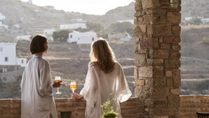 Dos personas sentadas en una mesa con vistas a edificios blancos y un paisaje montañoso.
