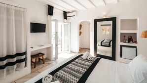 Habitación de hotel moderna con cama, televisor, escritorio y vistas al exterior.