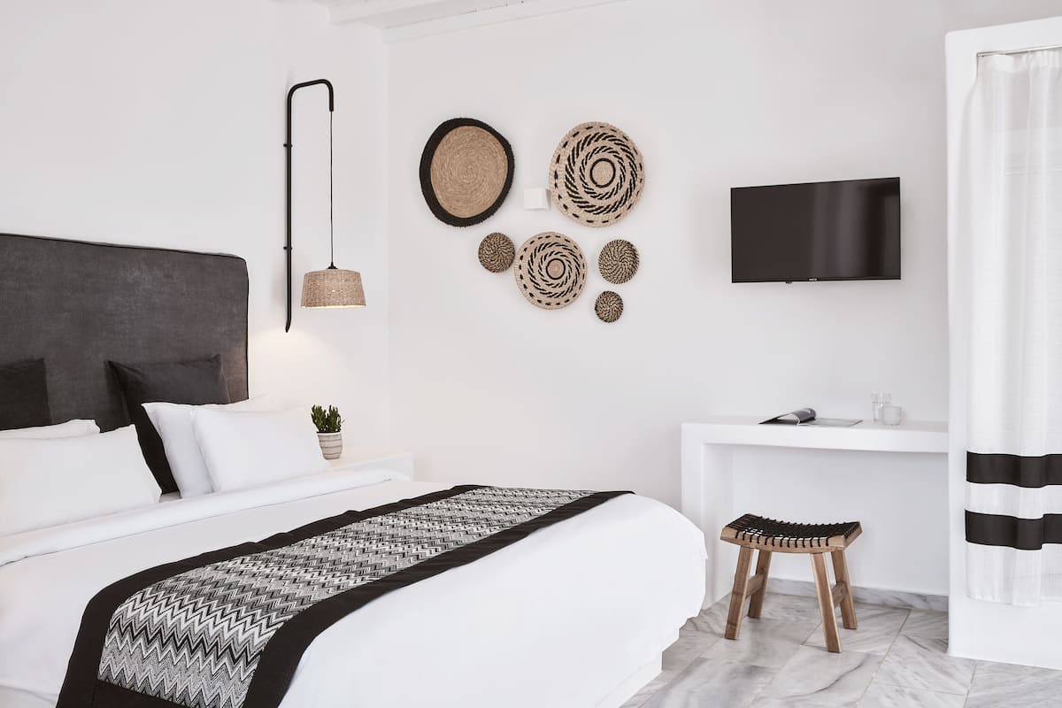 Une chambre moderne avec un grand lit, une table de chevet, une télévision et des éléments de décoration murale.