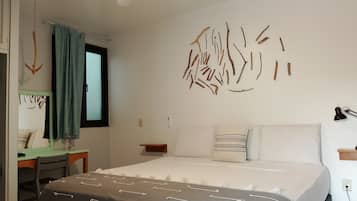 Un dormitorio con cama, mesitas de noche, un escritorio y un espejo.
