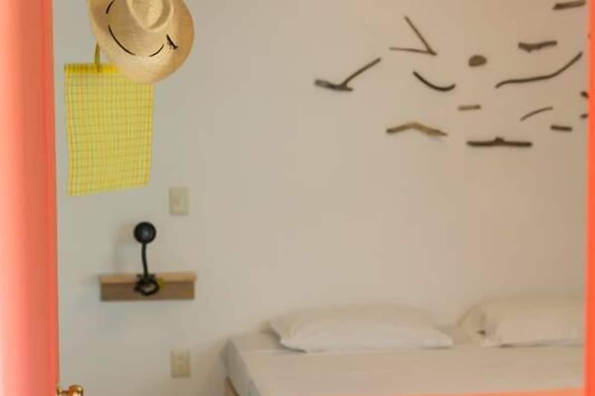 Une chambre avec un lit en bois, un chapeau suspendu, une étagère fixée au mur et une décoration murale représentant des oiseaux.