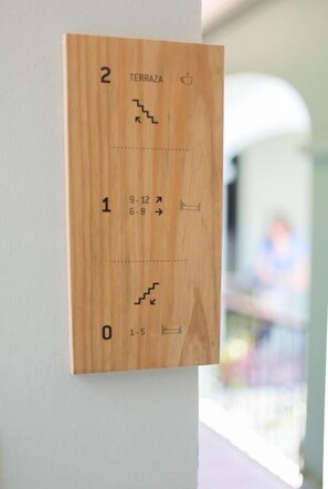Un panneau en bois fixé au mur, comportant des marches numérotées et des flèches indiquant la direction, et signalant la présence d’un escalier.