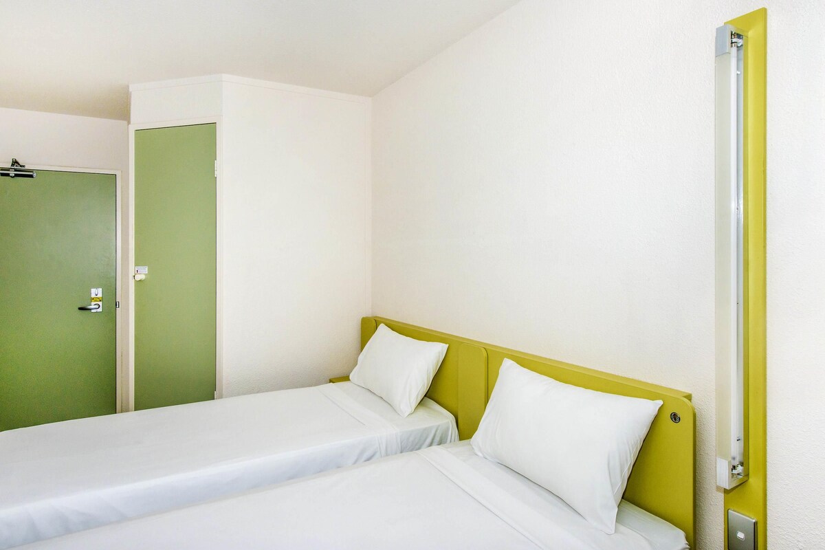 A room with two single beds, a green door, and a white wall.