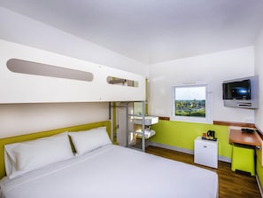 A hotel room with a bunk bed, a single bed, a TV, a window with a view, and a small desk with a coffee maker. - ibis Budget Dandenong (Dandenong)