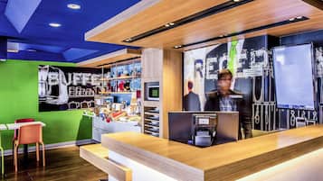 Un espace d’accueil moderne avec un comptoir en bois, un mur végétal et un coin café.
