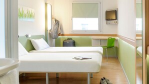 A hotel room with two beds, a desk, a chair, a TV, and a window. - ibis Budget Dandenong (Dandenong)