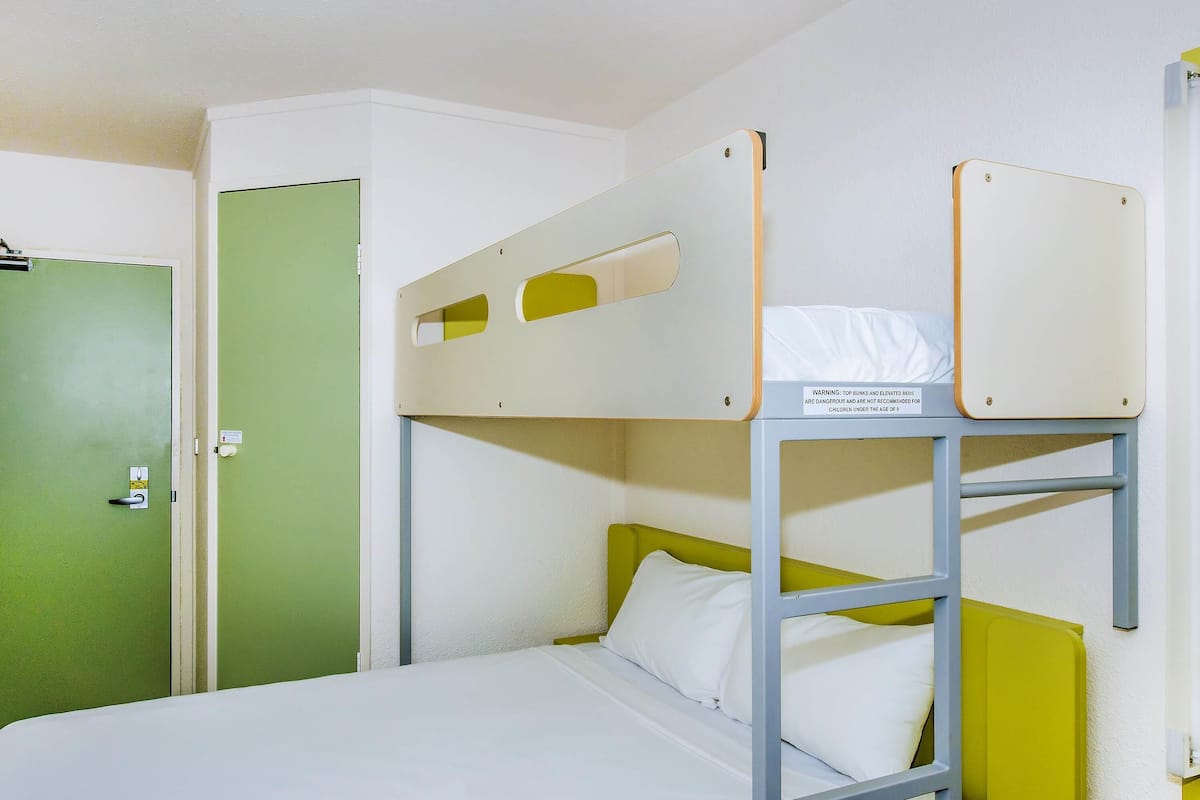 A bunk bed with a warning sign, a green door, and a white wall.