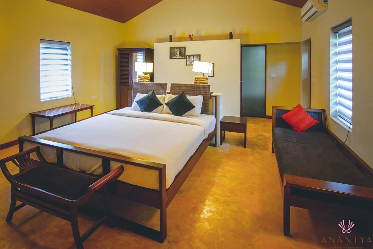 A hotel room with a large bed, a sofa, a desk, and a chair.