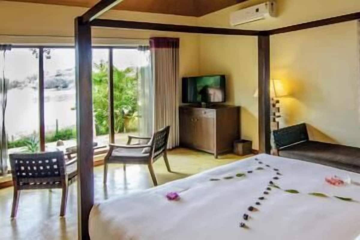 A hotel room with a bed, a desk, a chair, and a window with blinds.