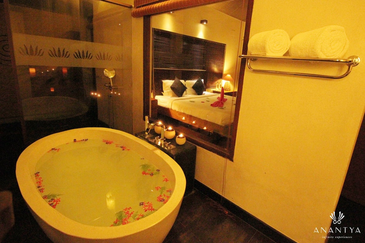 A bathroom with a large bathtub, a mirror, and a towel rack.