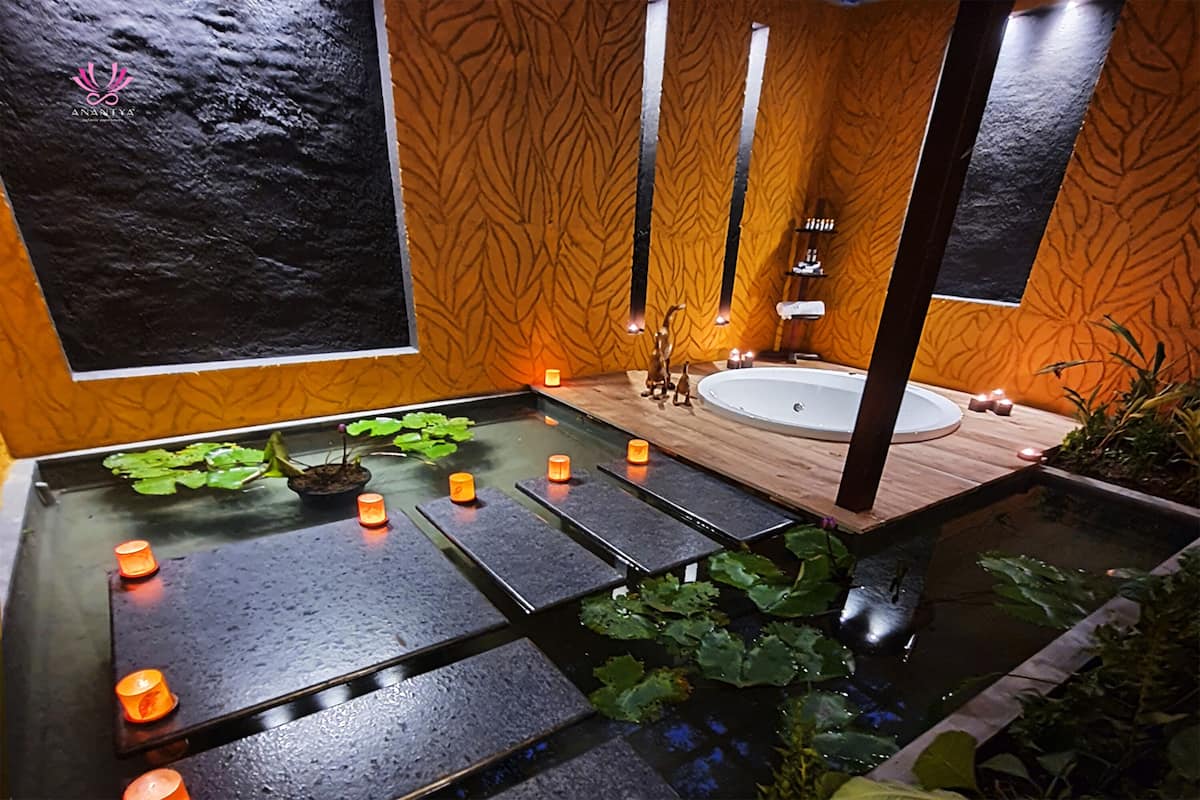 A spa area with a hot tub, candles, and a water feature.