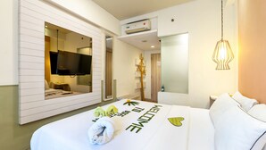 A hotel room with a bed, a TV mounted on the wall, an air conditioning unit, and a hanging light fixture. - Boss Legian Hotel Powered by Archipelago (Legian)