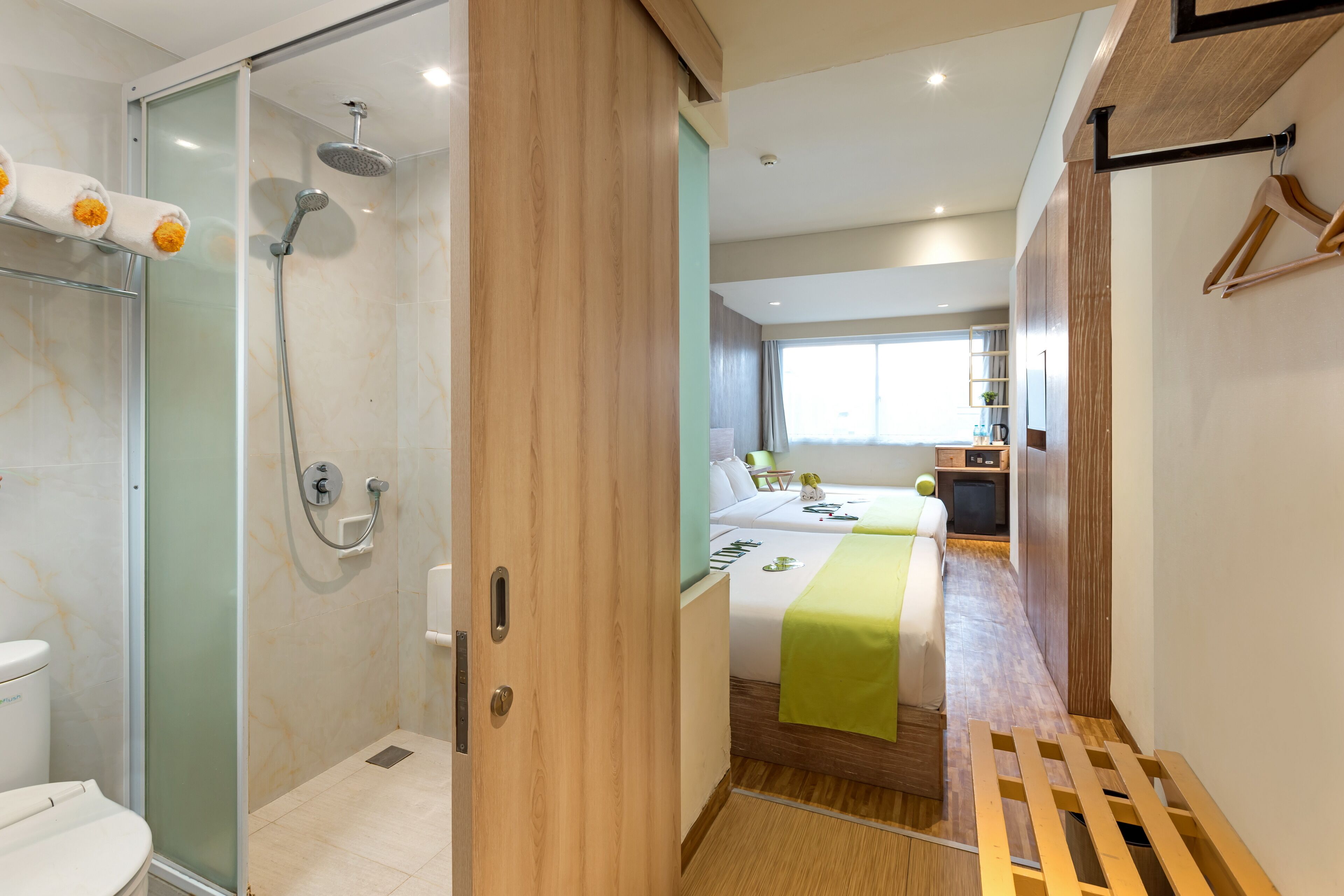 A modern bathroom with a glass-enclosed shower, a toilet, and a wooden floor.