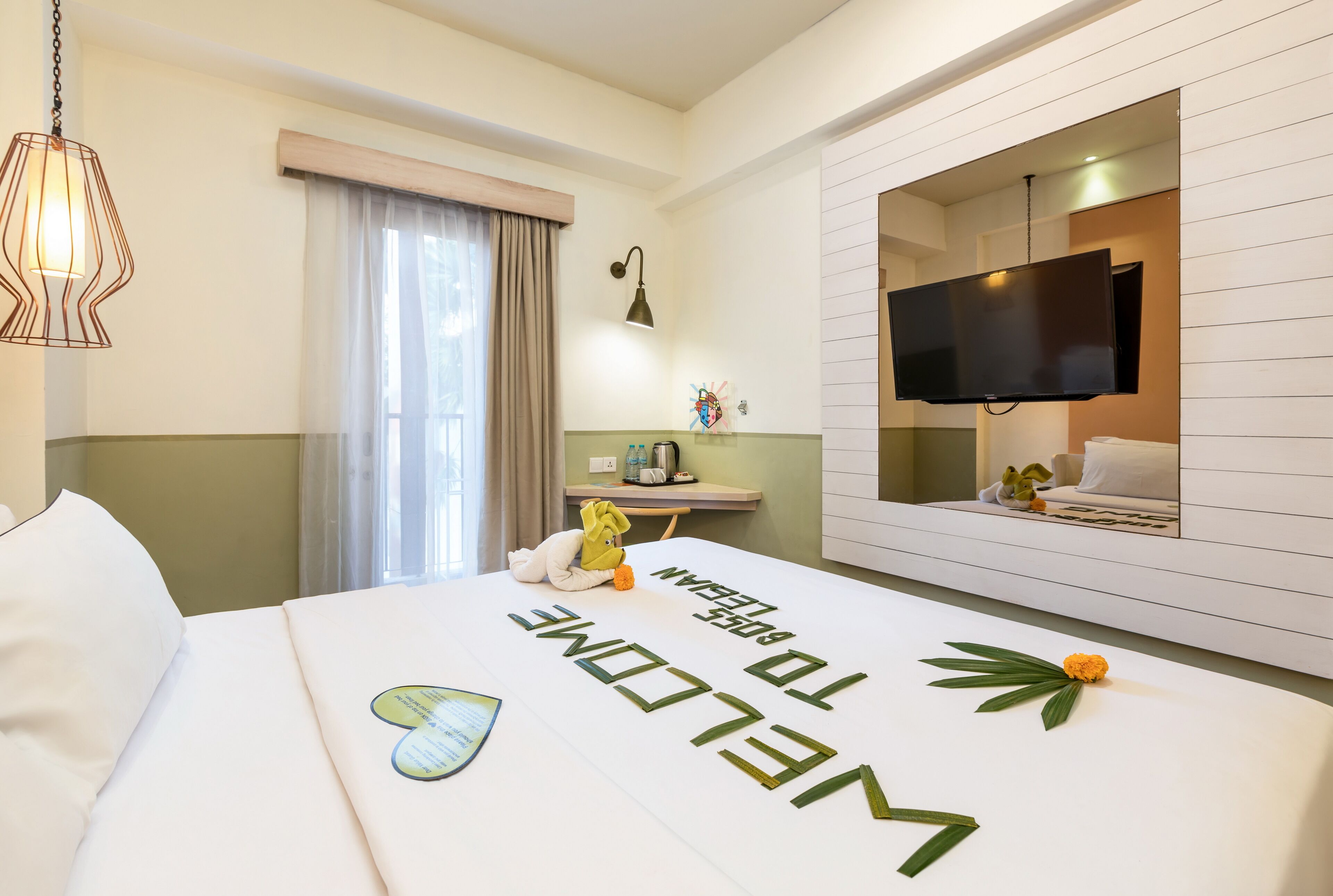 A hotel room with a bed, a desk, a television, and a window with curtains.