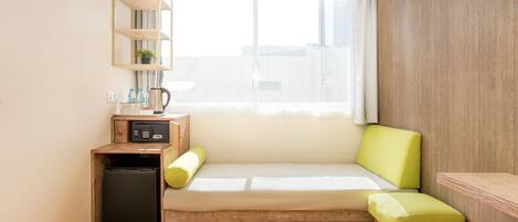 A compact room with a sofa, a small table, a microwave, and a compact refrigerator.