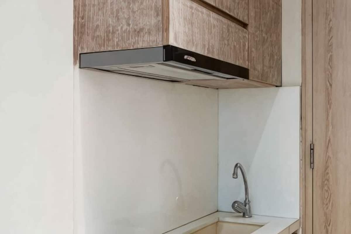 Eine KĂŒche mit Einbaukoje, SpĂŒle aus Edelstahl und HolzschrĂ€nken.