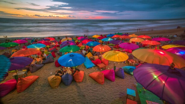 A beach with colorful umbrellas and bean bags, providing shade and seating for visitors. - Boss Legian Hotel Powered by Archipelago (Legian)