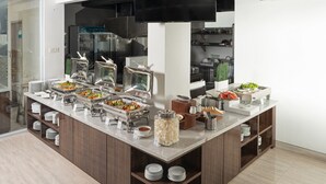 A buffet setup with various food stations, including a salad bar, a hot food station, and a beverage dispenser. - Boss Legian Hotel Powered by Archipelago (Legian)