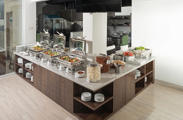 Tarjolla on runsas buffet, jossa on useita eri ruokapisteitä, kuten salaattibaari, lämpimien ruokien piste ja juoma-automaatti.