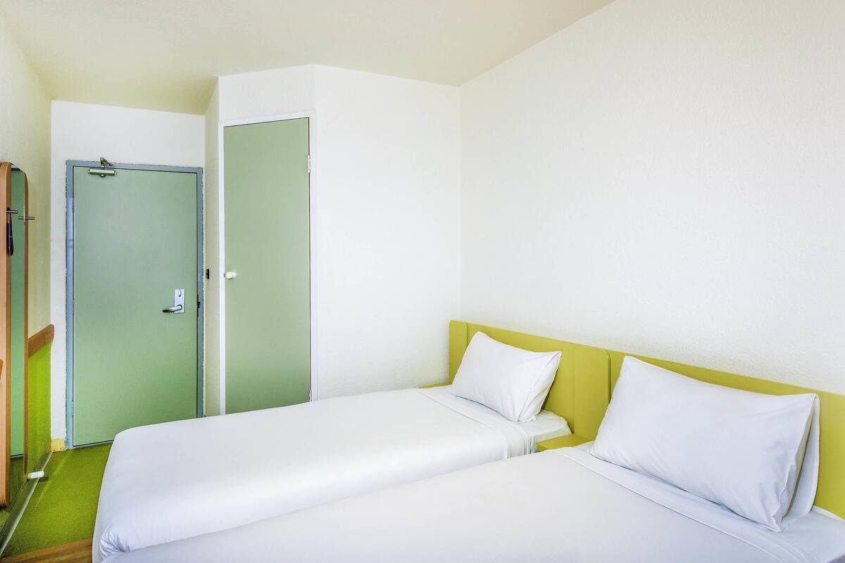 A room with two beds, a green door, and a white wall.