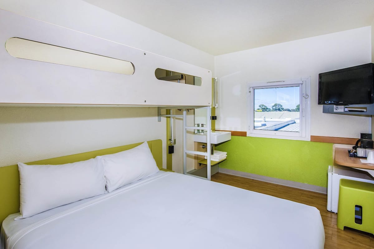 A bunk bed room with a television, a window, and a sink.