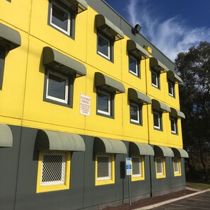 A multi-story yellow building with multiple windows and a sign indicating customer parking.