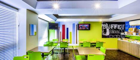 Un interior moderno con una larga mesa y sillas, un televisor y una zona de bufé.