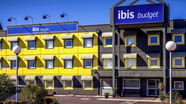 A building with a sign reading "ibis budget" and a yellow facade.