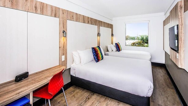 Een moderne hotelkamer met een groot bed, een bureau en een televisie.