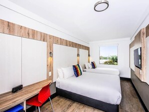 Una habitación de hotel moderna con una cama grande, un escritorio y un televisor.