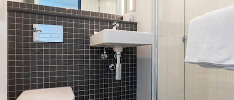 Un baño con inodoro blanco, lavamanos y cabina de ducha de vidrio.