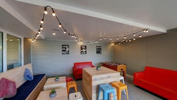 Een moderne lounge met een tafelvoetbalspel, rode en blauwe krukken en een tafelvoetbaltafel.