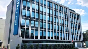 Een modern gebouw met een grote glazen gevel en een blauw bord waarop 'budget' staat.