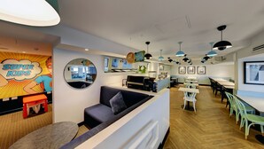 Een modern café interieur met een balie, zitgedeelte en kunstwerken aan de muren.