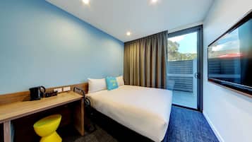 Een hotelkamer met een bed, een bureau, een stoel, een koffiezetapparaat en een televisie.