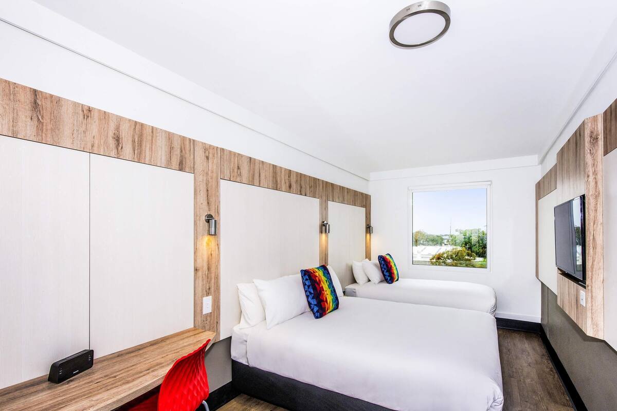 Een moderne hotelkamer met een groot bed, een bureau en een aan de muur bevestigde televisie.