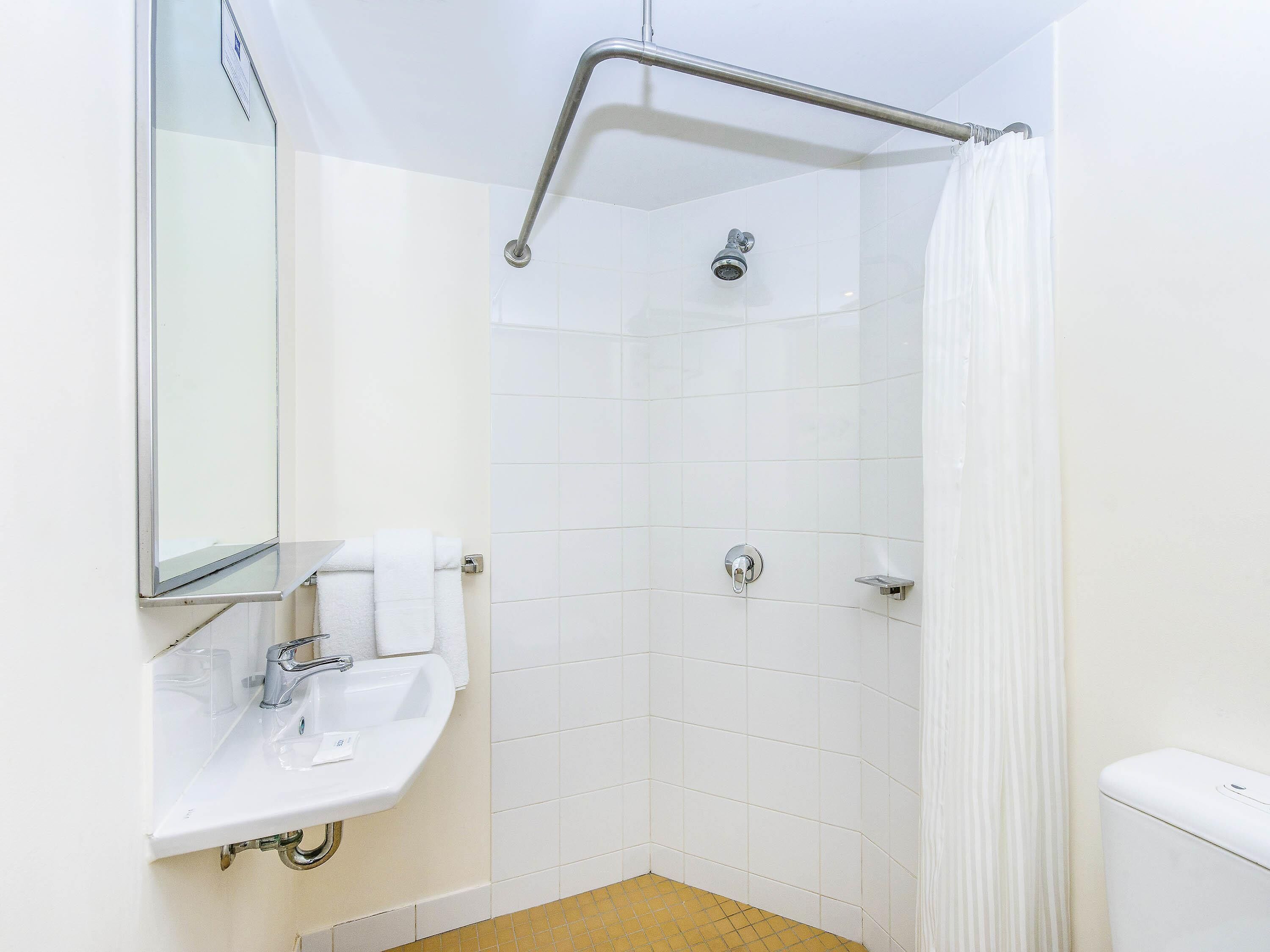 A bathroom with a shower, a sink, a toilet, and a mirror.