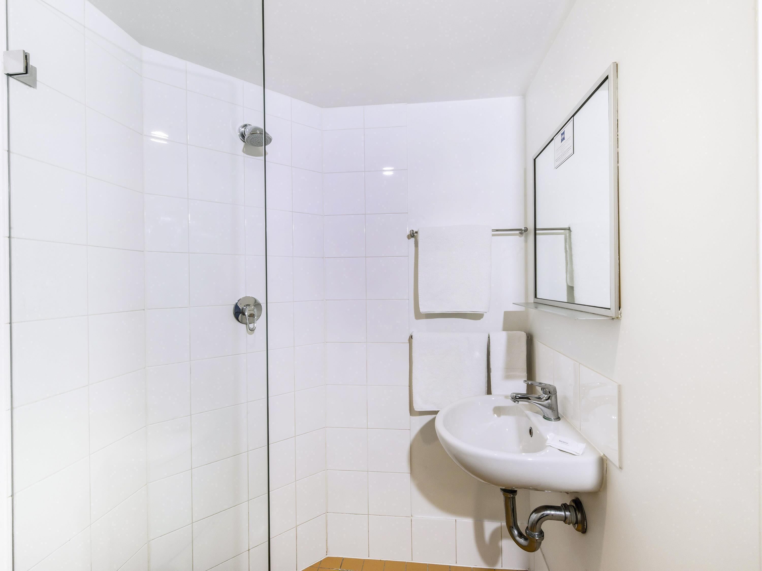 Une salle de bain moderne avec une douche à parois de verre, un lavabo blanc et un miroir.