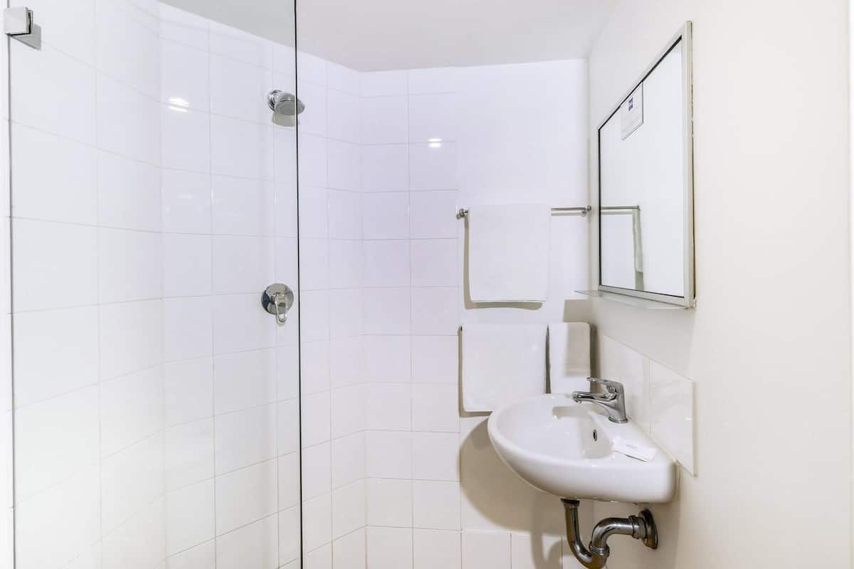 Une salle de bain moderne avec une douche à parois de verre, un lavabo blanc et un miroir.