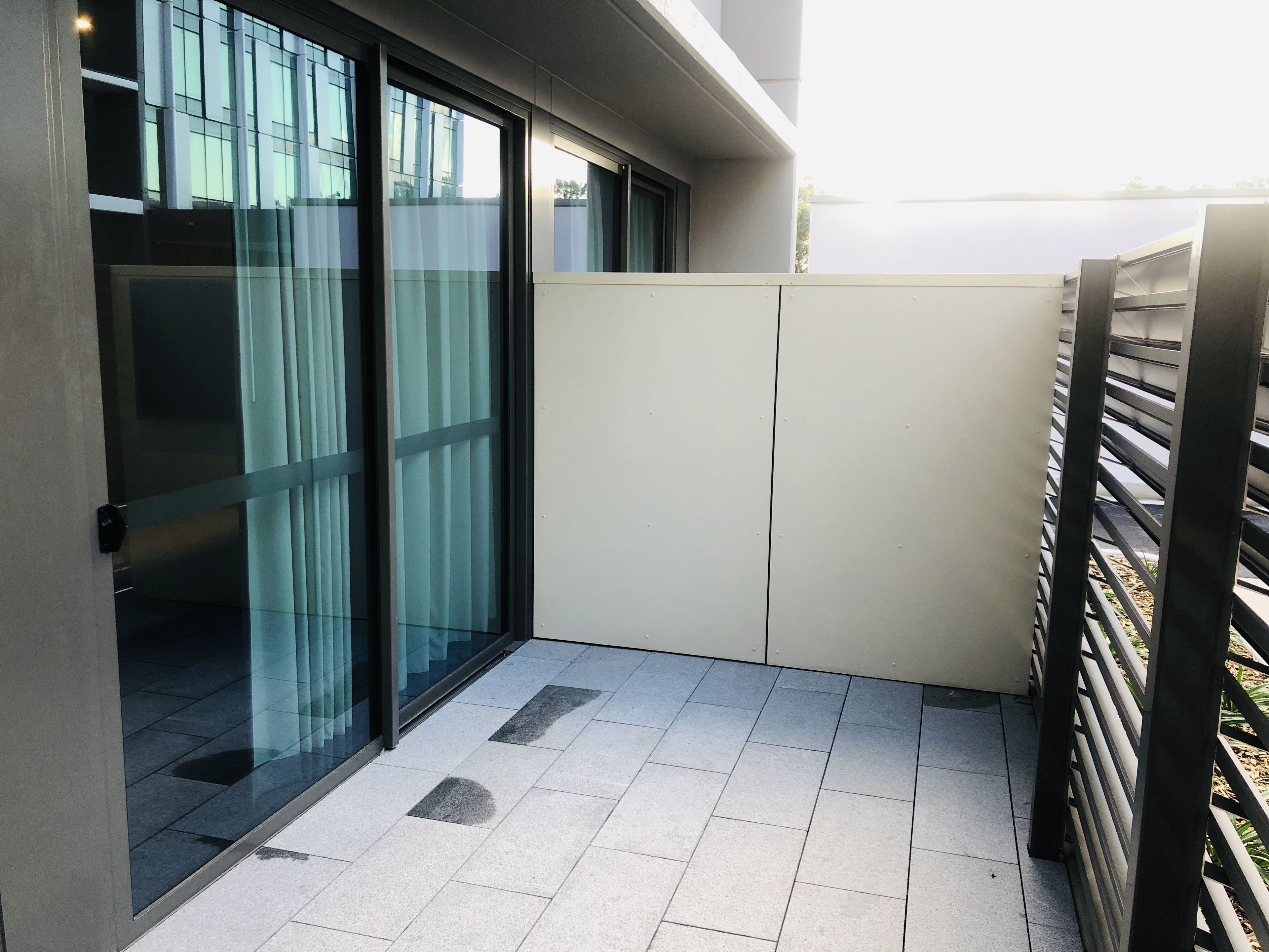 A modern building with large glass windows, a tiled floor, and a metal fence.