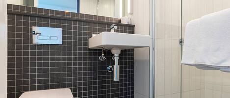 A modern bathroom with a toilet, sink, and glass shower enclosure.