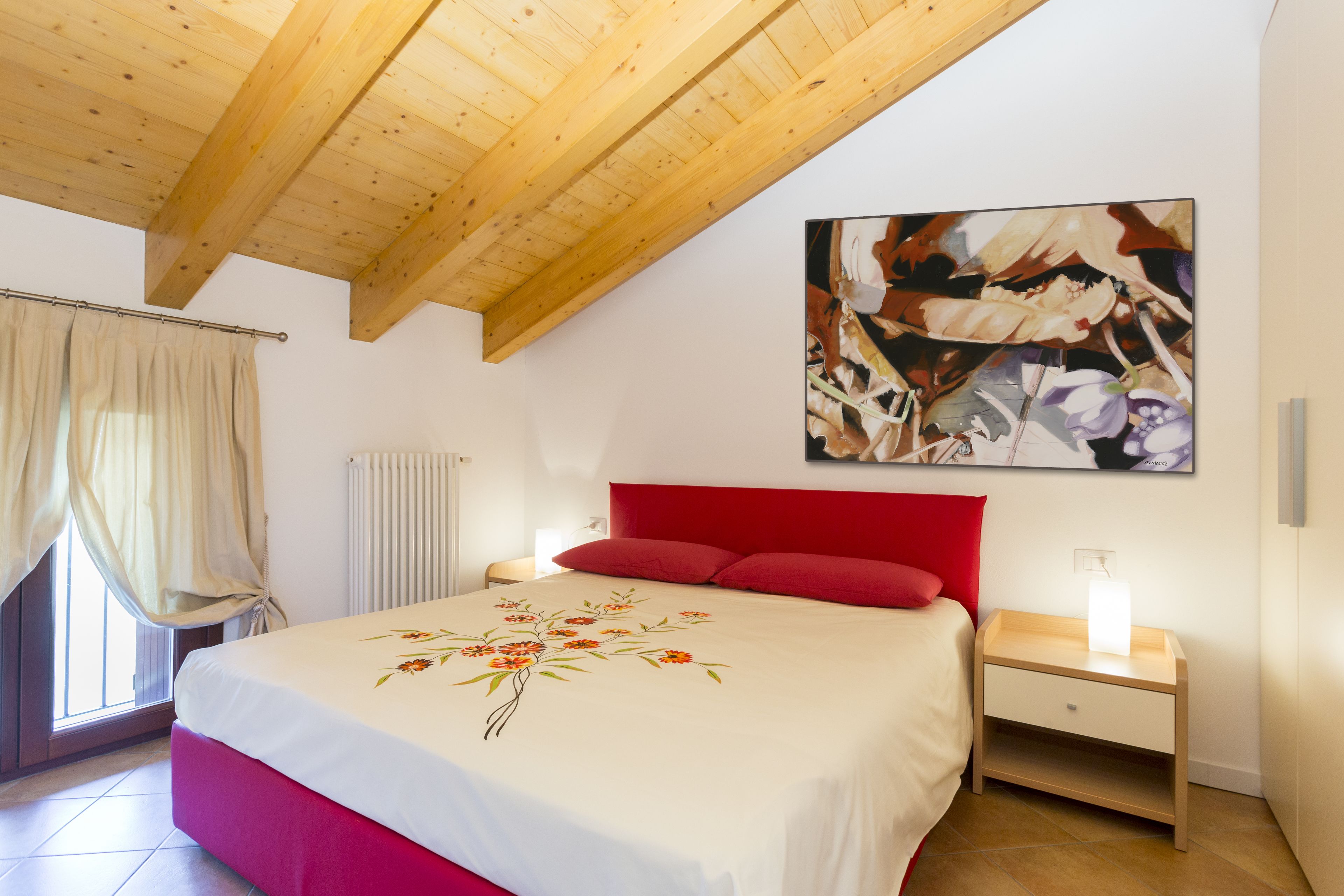 Ein Schlafzimmer mit einem Bett, einem roten Kopfteil und einem Nachttisch mit einer Lampe.