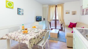 Un espace de vie compact comprenant un coin repas, une kitchenette et un canapé.