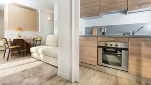 Une cuisine moderne avec des meubles en bois, un four encastré et un coin repas comprenant une table et des chaises.