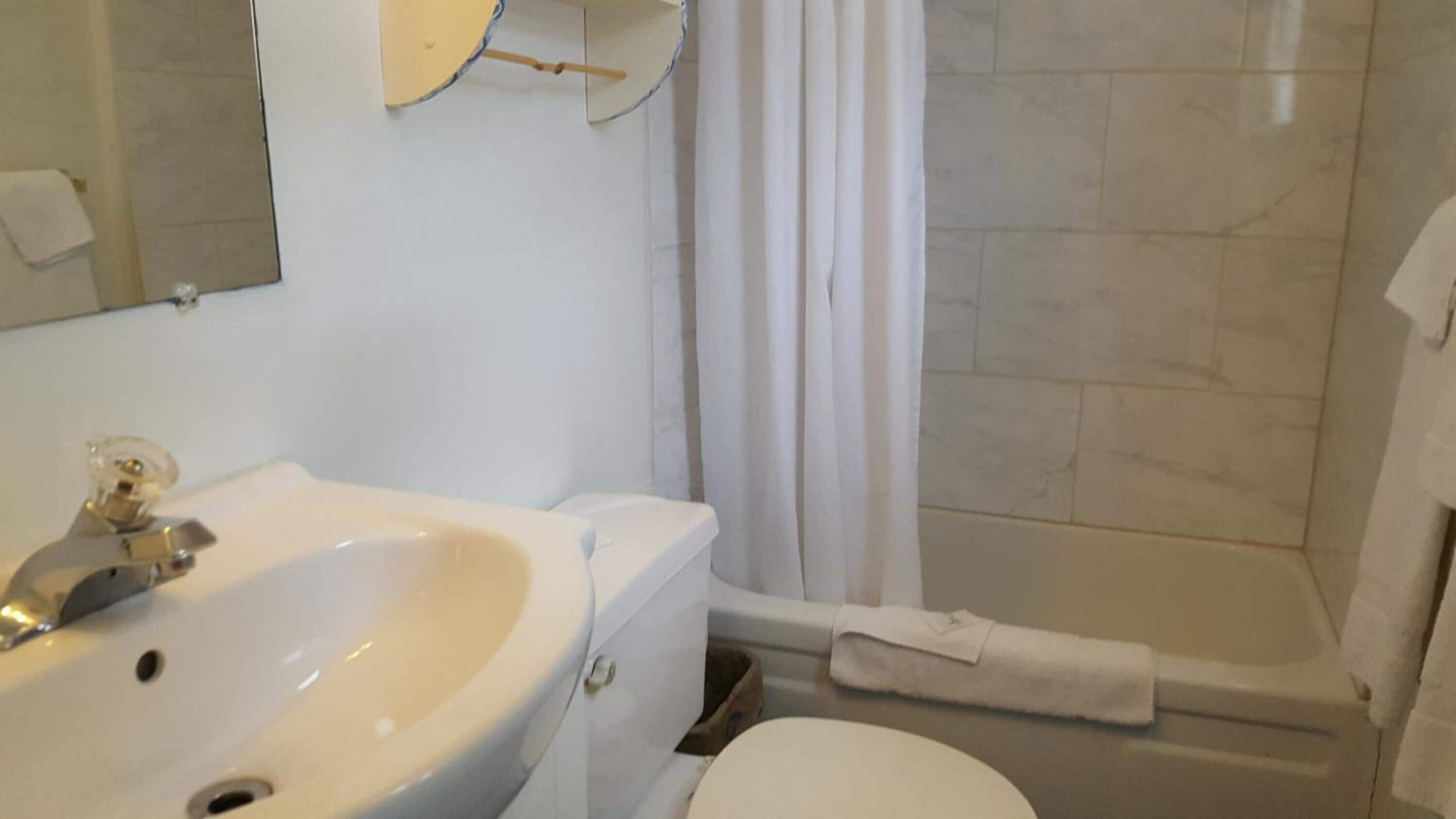 A bathroom with a sink, mirror, and shower area.