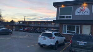 A motel with a sign reading "All Seasons Motel" and a parking lot with several cars.
