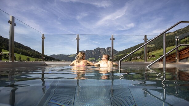 A swimming pool with metal railings and a view of mountains in the background. - Galtenberg Family & Wellness Resort (Alpbach)