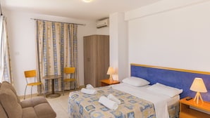 A hotel room with a bed, two chairs, a small table, a sofa, and a wardrobe. - Alecos Hotel Apartments (Paphos)