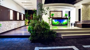 A modern lobby with a large aquarium, seating area, and decorative plants. - D&G Villas (Nusa Dua)